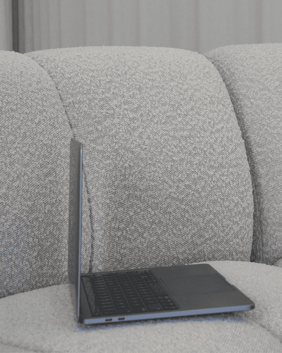 Minimalist photo of a sleek laptop on a textured grey sofa, representing digital strategy and website conversion for creative business owners.