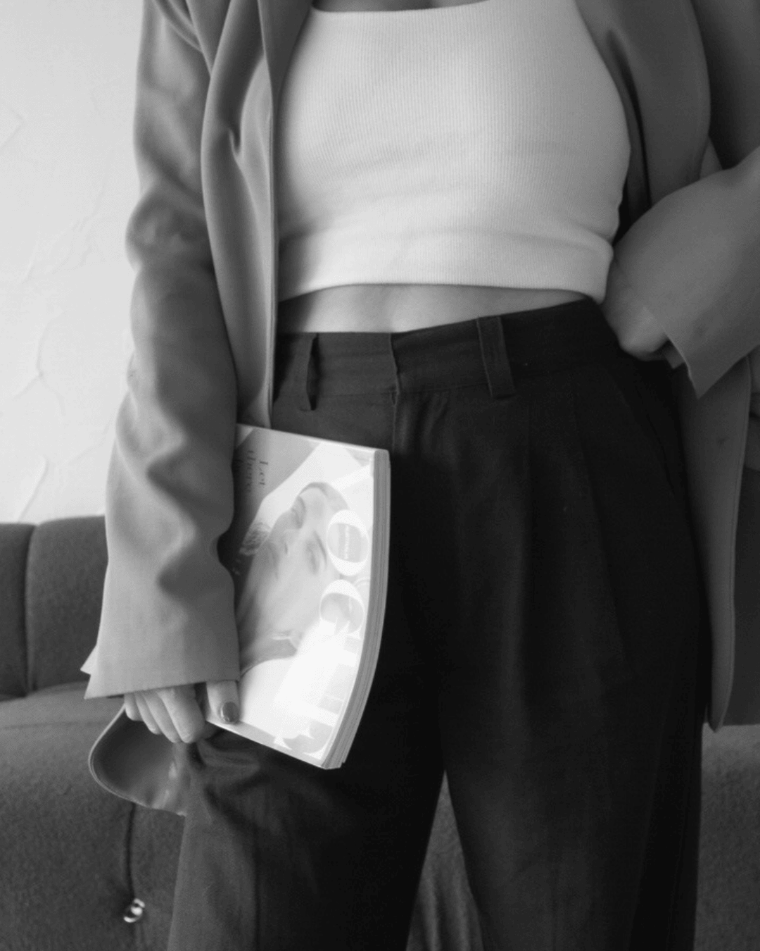 Black and white photo of a woman in tailored trousers and blazer holding a Vogue magazine—styled with a modern, minimalist editorial feel that speaks to premium brand elevation.